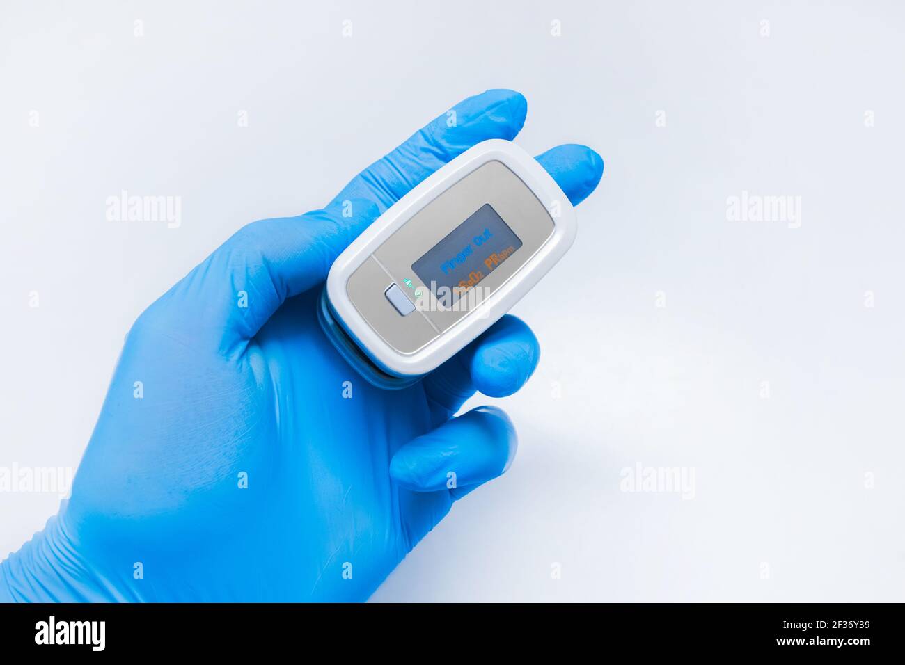 Arzt Hand in schützende medizinische Handschuhe halten moderne Fingerspitze Pulsoximeter auf einem weißen Hintergrund, Nahaufnahme. Stockfoto