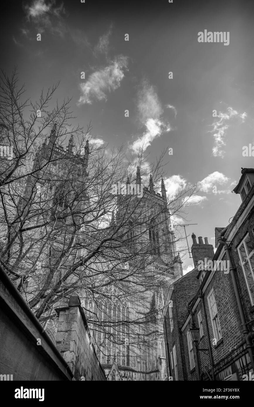 Die Westtürme des York Minster erheben sich über den Häusern einer nahe gelegenen Straße. Ein Himmel mit Wolken ist oben. Stockfoto