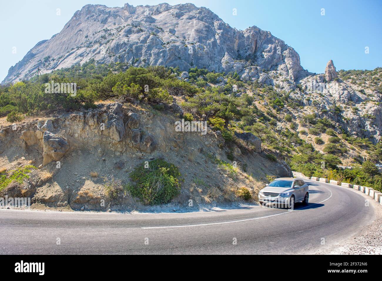 Crossover bewegt sich entlang einer kurvenreichen Straße in den Bergen während Der Tag Stockfoto