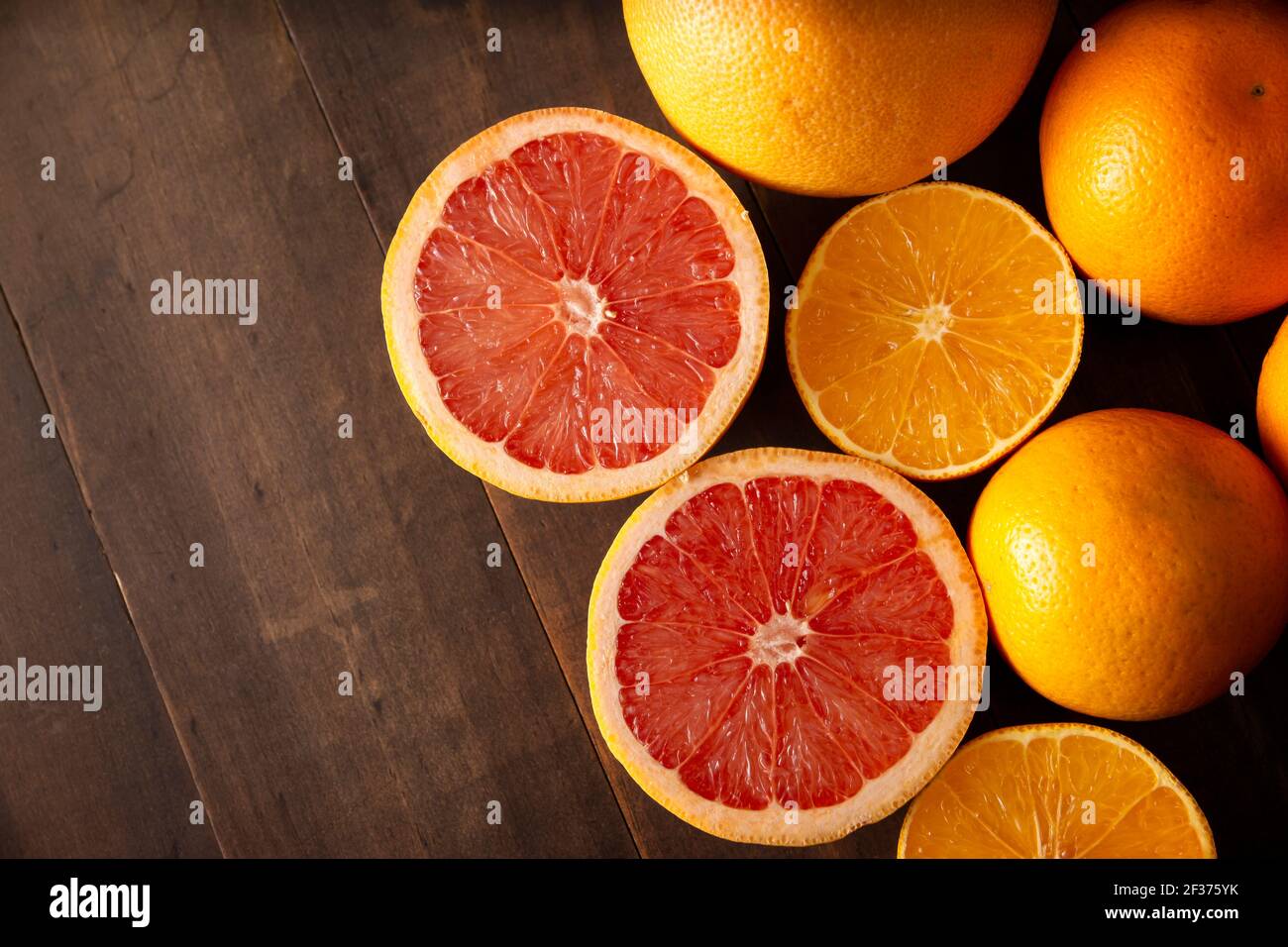Flach Lay Bild von reifen Orange und Grapefruit Scheiben und Mehrere ganze Orangen auf braunem rustikalem Holztisch mit Kopie Platz Stockfoto