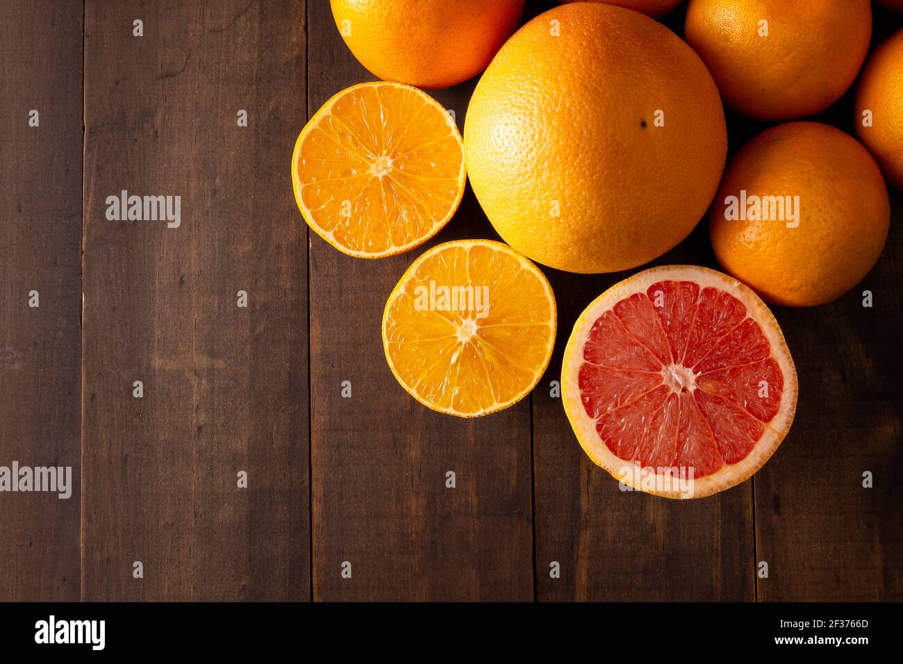 Draufsicht Bild von reifen Orange und Grapefruit Scheiben und Mehrere ganze Orangen auf braunem rustikalem Holztisch mit Kopie Platz Stockfoto