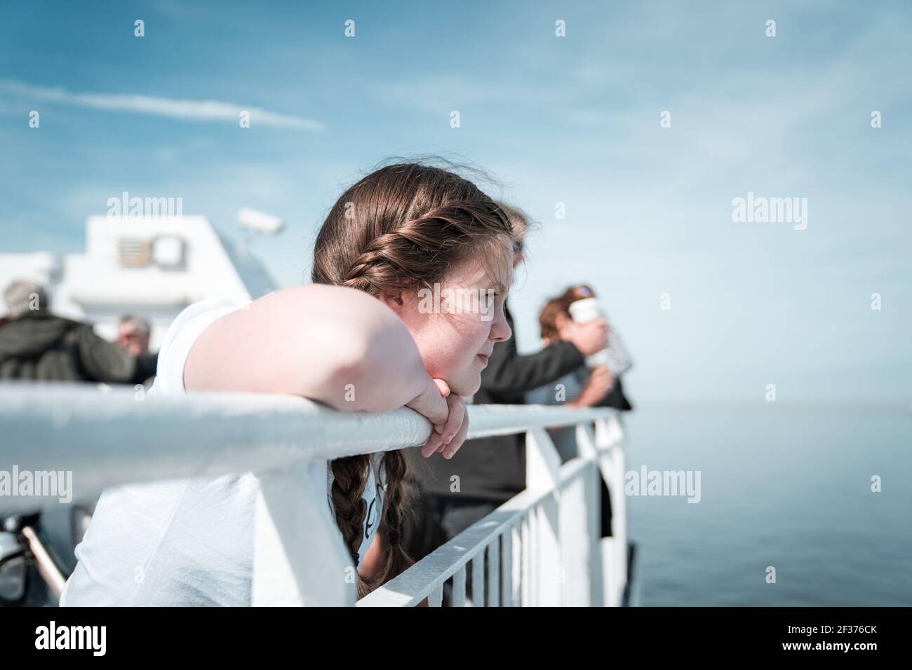 Junge hübsche Mädchen in Sonnenschein auf Schiff Boot Deck suchen Segeln auf dem Meer weg vom Hafen blauen Sommer Himmel Stockfoto