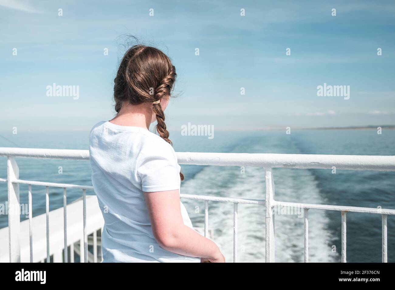 Junge hübsche Mädchen in Sonnenschein auf Schiff Boot Deck suchen Segeln auf dem Meer weg vom Hafen blauen Sommer Himmel Stockfoto