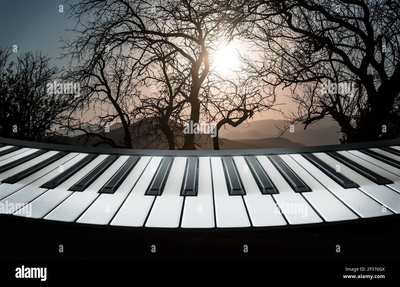 Klaviertasten vor der Kulisse einer Berglandschaft mit Bäume und Sonnenuntergang Stockfoto