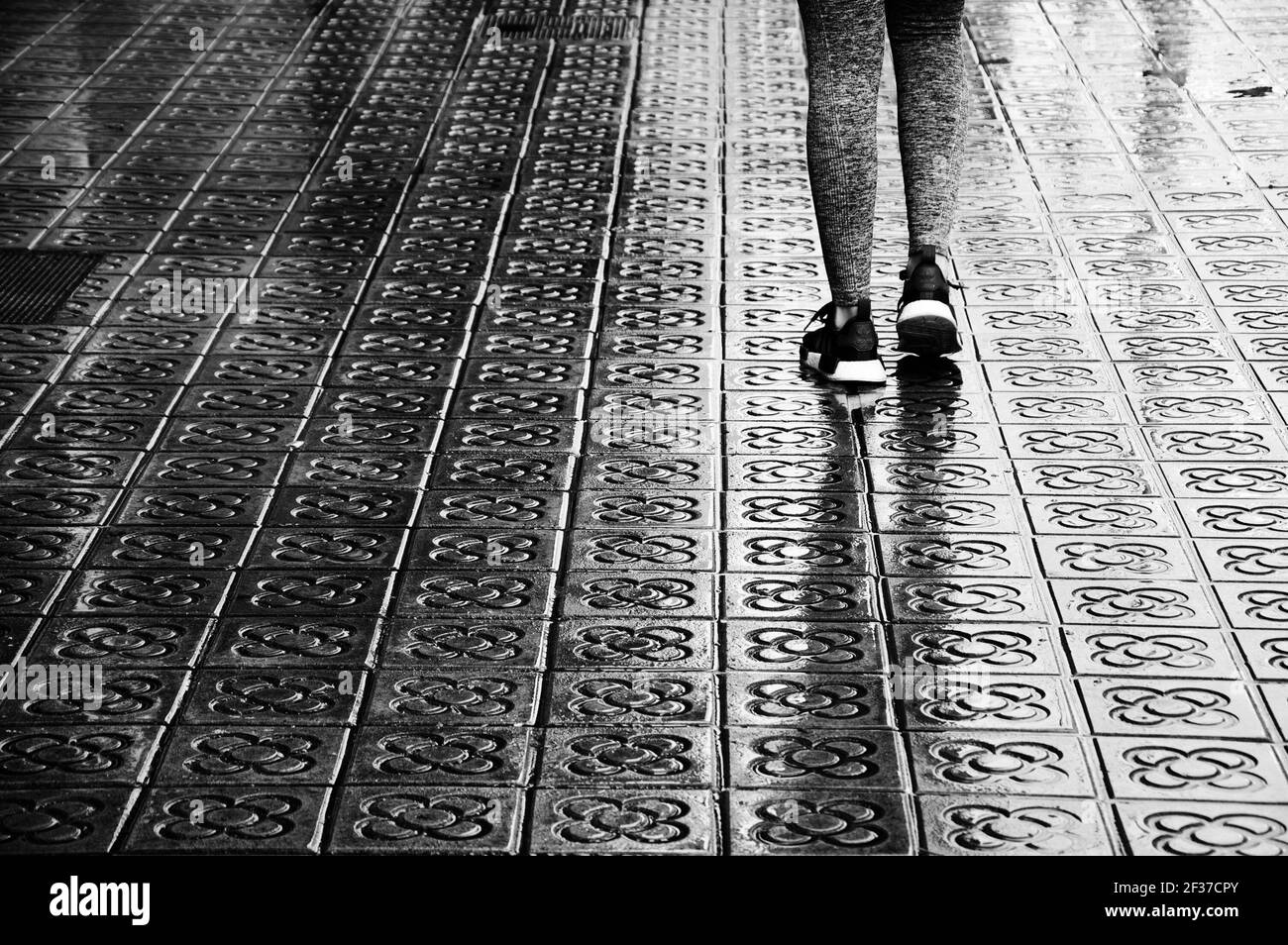 BARCELONA, SPANIEN - 11. MÄRZ 2018: Adidas Beliebte Sneakers Schuhe auf  Jogging weiblichen Beinen auf nassen Blumen Straßenpflaster. Schwarz weiß  historisches Foto Stockfotografie - Alamy