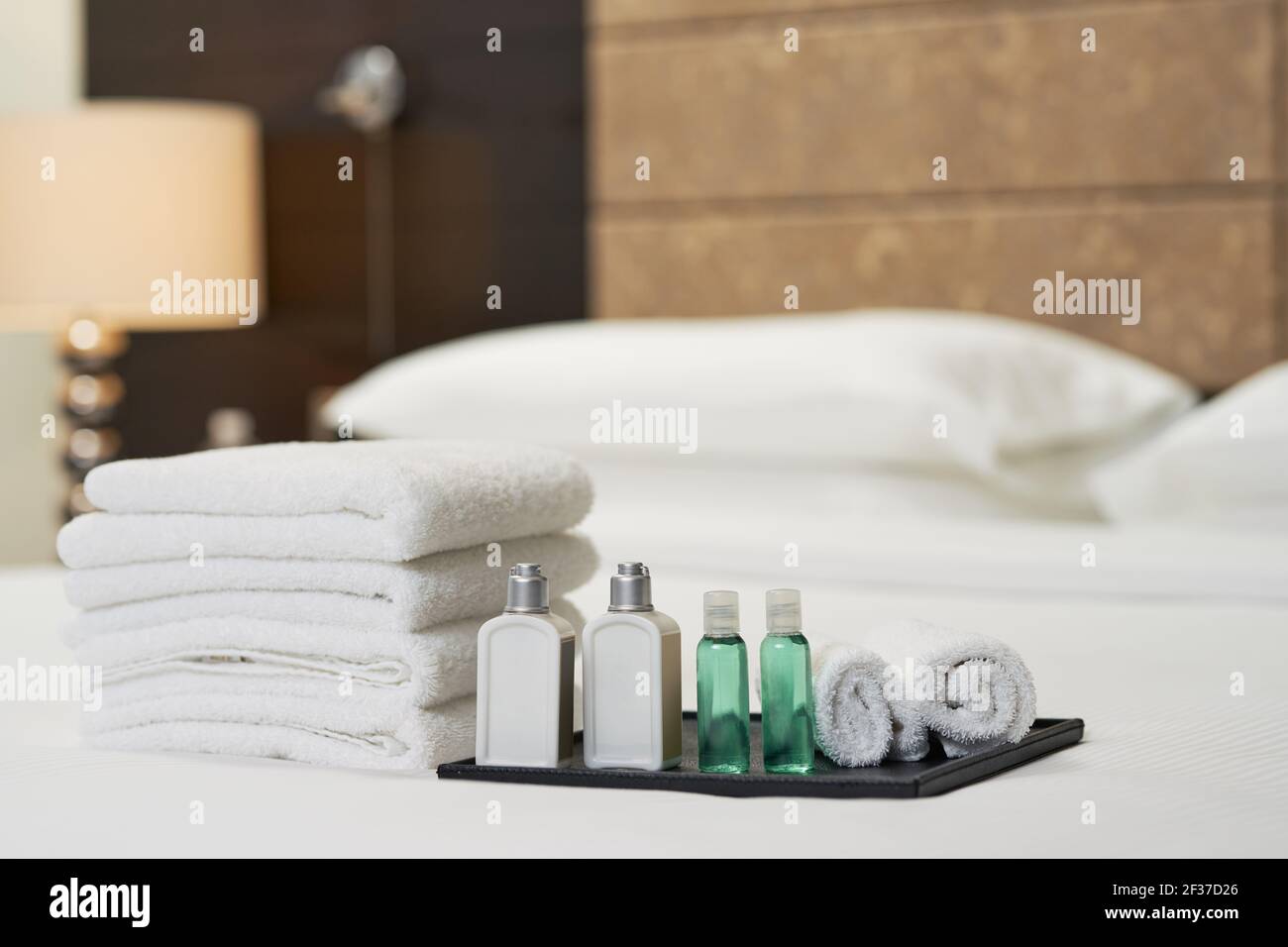 Flüssiges Shampoo und Duschgel neben Handtüchern auf dem Bett Stockfoto