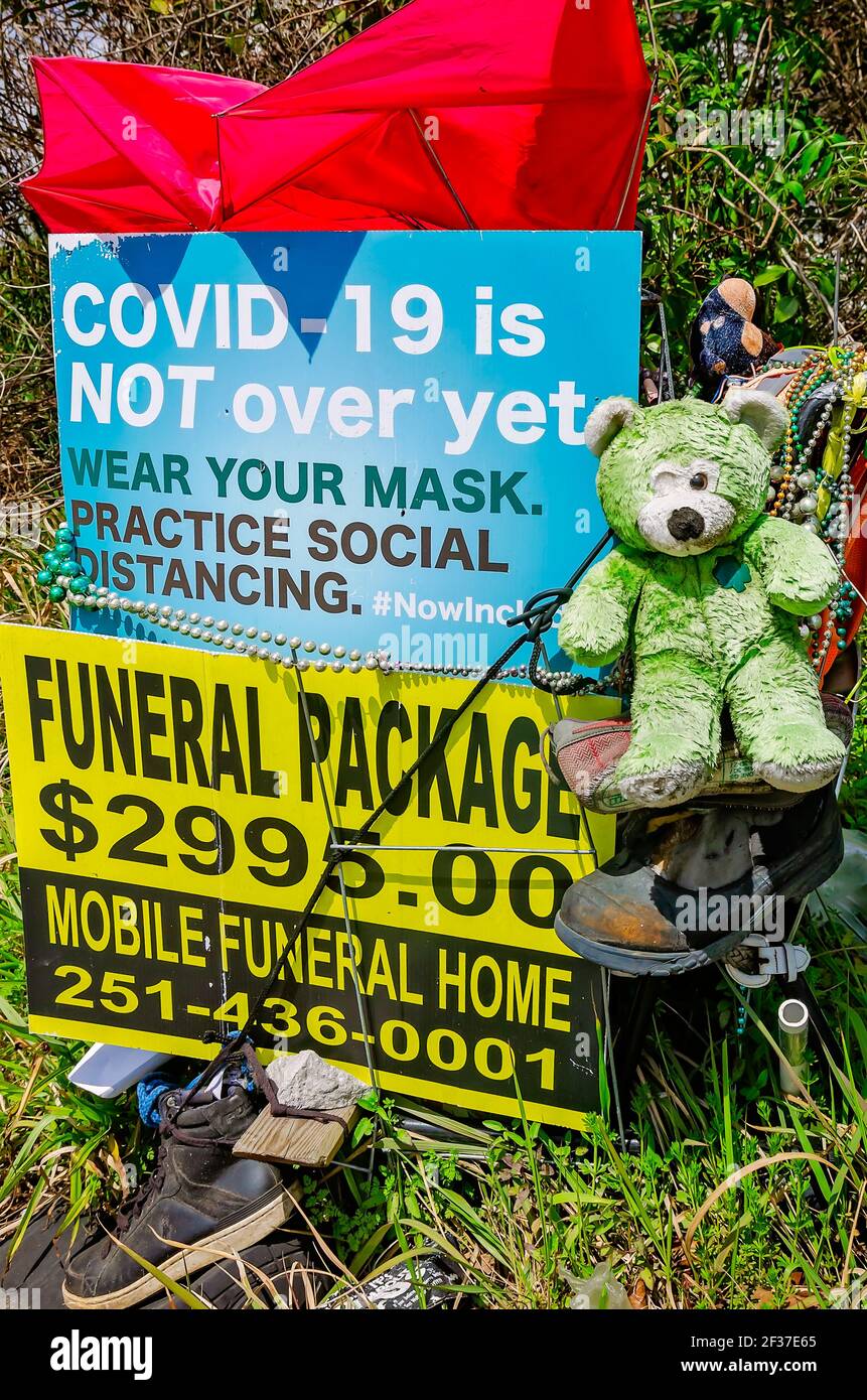 Eine Gedenkkunst-Ausstellung am Straßenrand beinhaltet ein Schild über COVID-19, eine Bestattungswerbung und andere Gegenstände in Prichard, Alabama. Stockfoto