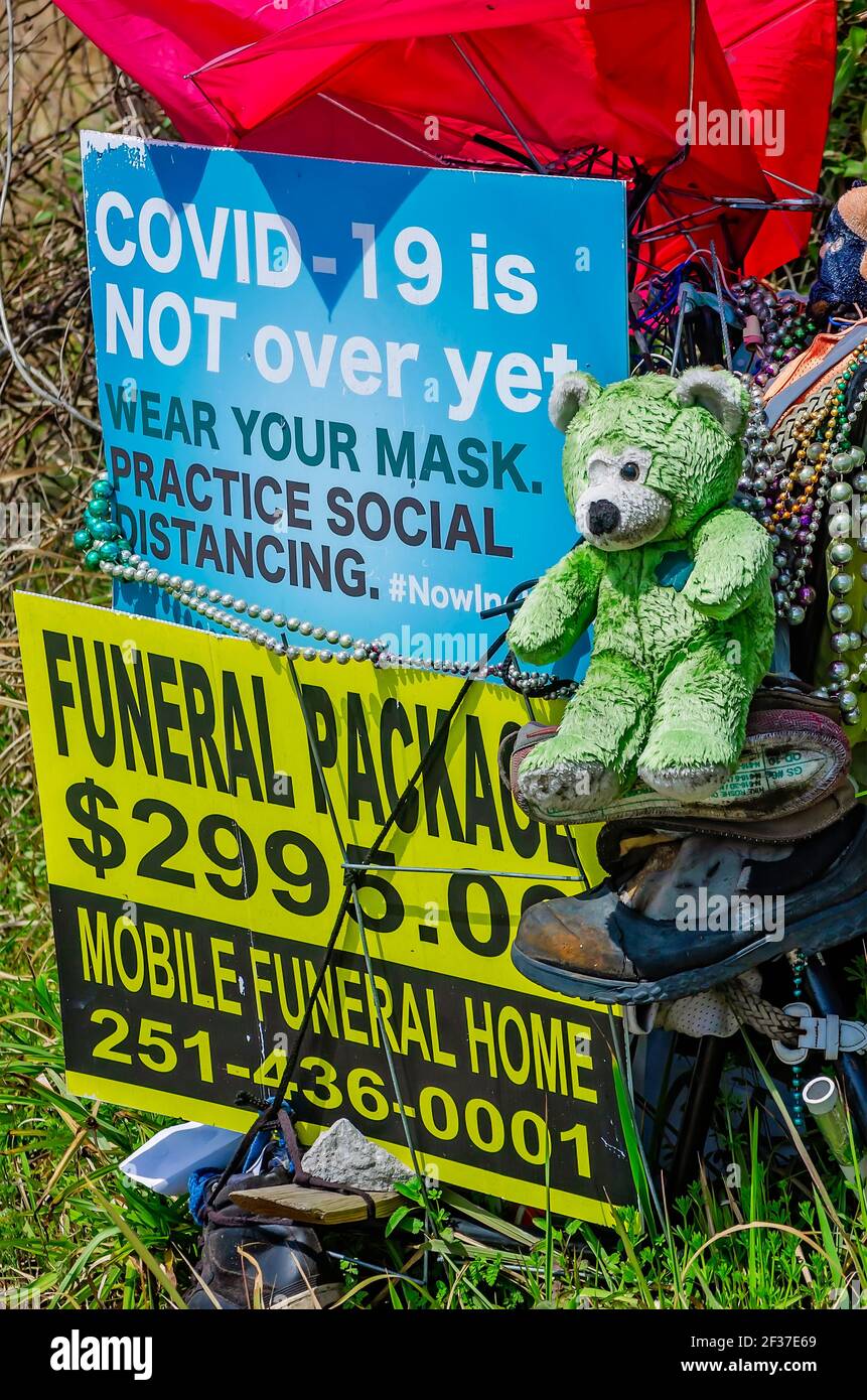 Eine Gedenkkunst-Ausstellung am Straßenrand beinhaltet ein Schild über COVID-19, eine Bestattungswerbung und andere Gegenstände in Prichard, Alabama. Stockfoto
