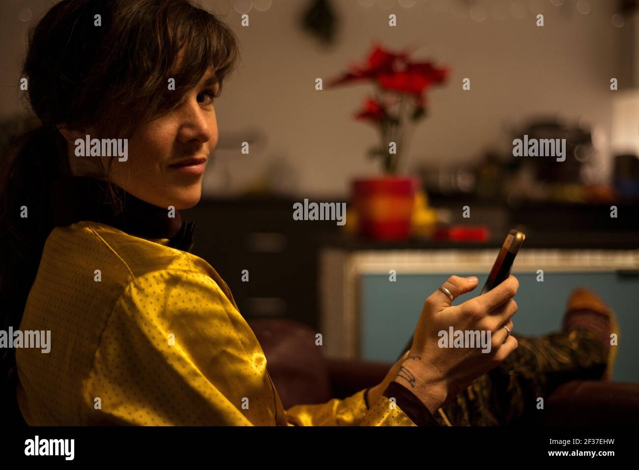 Sommersprossen Frau schaut zur Kamera, während sie am Telefon tippt Zuhause bei Nacht Stockfoto