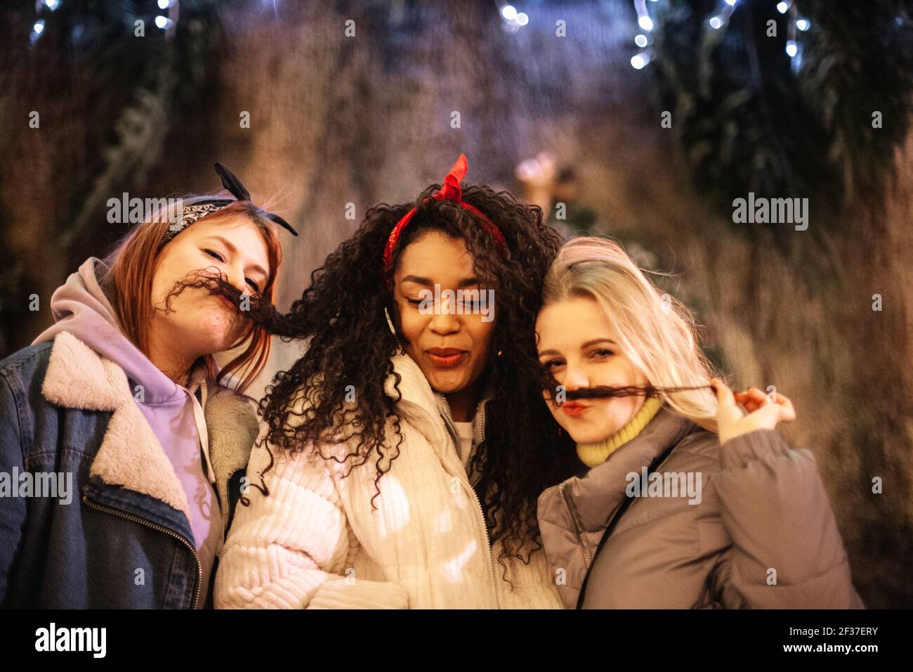 Junge Frauen machen gefälschte Schnurrbärte mit ihrer Freundin die Haare in Stadt Stockfoto
