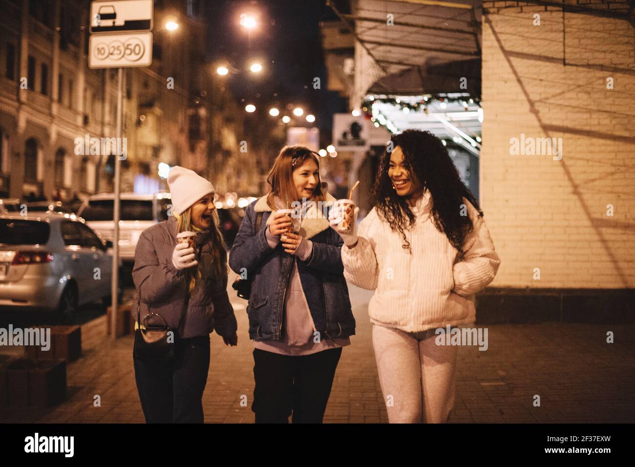 Glückliche Freundinnen, die heiße Getränke auf der Straße trinken Stadt Stockfoto