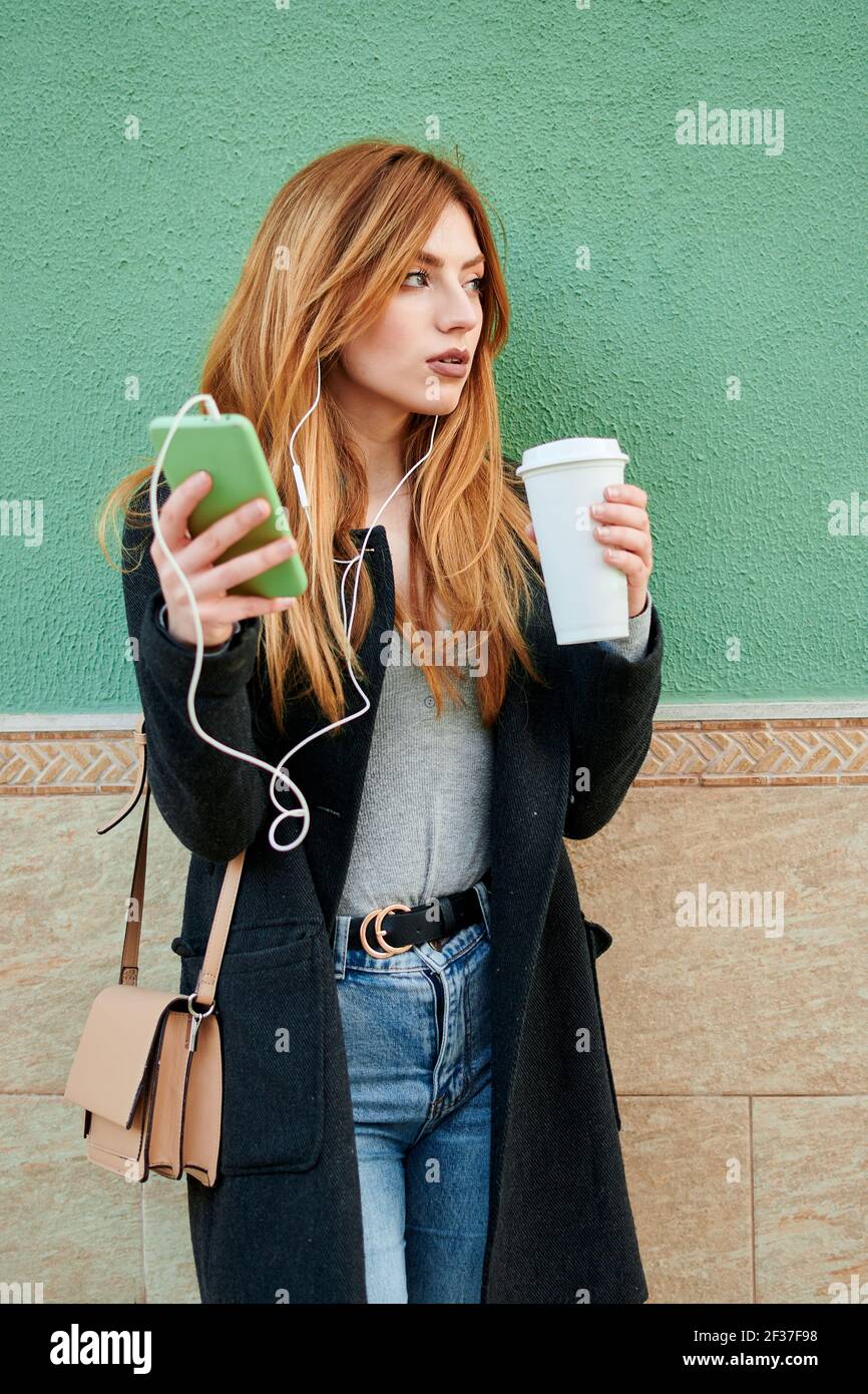 Geschäftsfrau hält eine Kaffeetasse, während sie schaut Am Telefon Stockfoto
