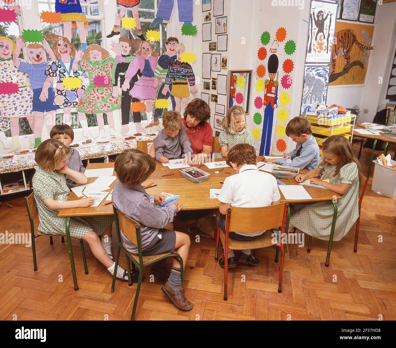 Lehrer hilft Grundschulkinder in der Kunstklasse, Surrey, England, Großbritannien Stockfoto