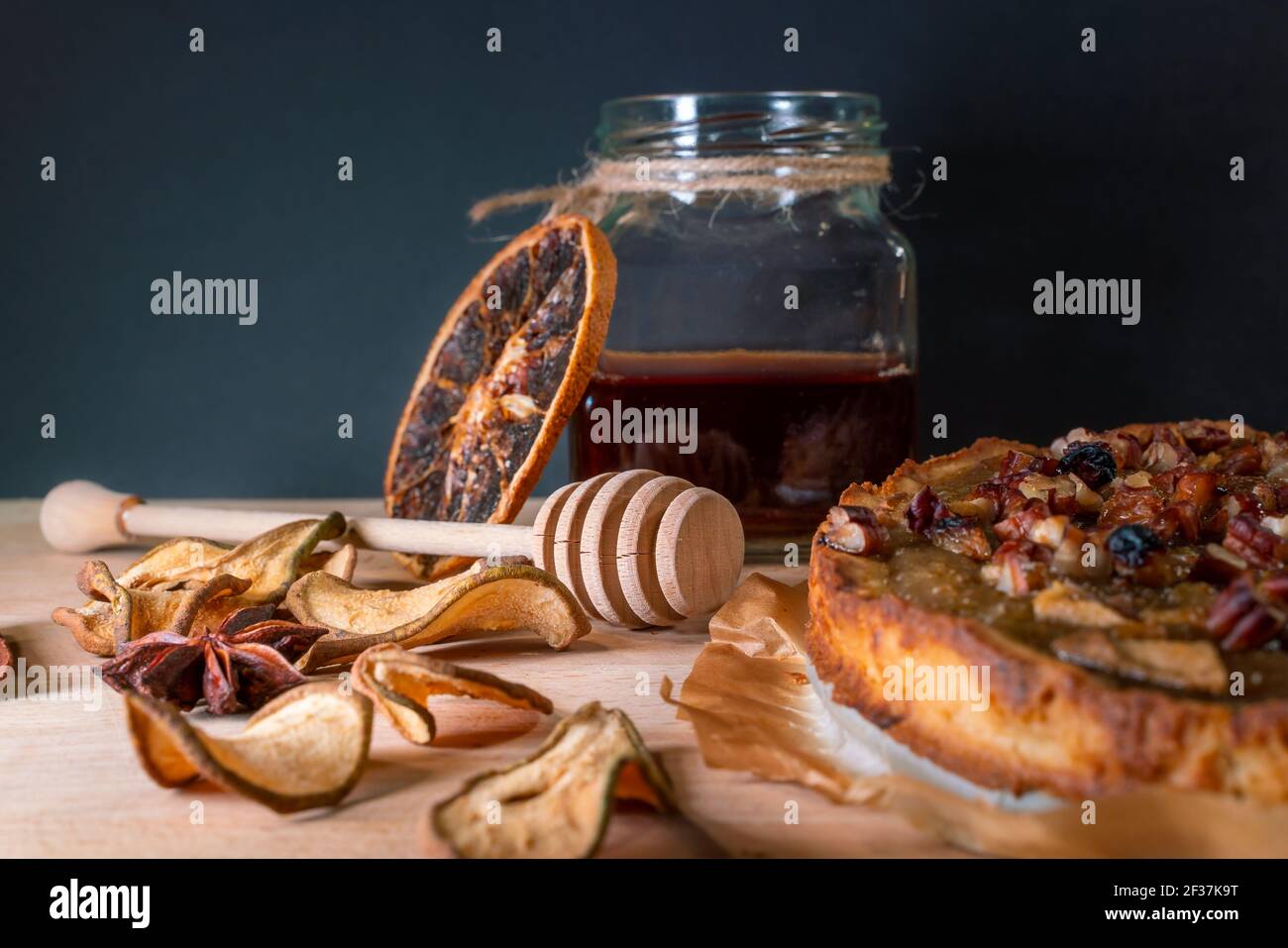 Stillleben mit hausgemachtem Bio-Essen. Birnenkuchen, Glas mit Honig und Dipper, Zimt, getrocknete Früchte, Nüsse. Gesundes Frühstück ohne Zuckerzusatz. Gesund Stockfoto