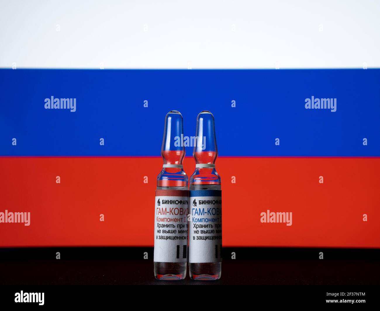 Russische Sputnik V-Impfstoff (GAM COVID) Darstellung Flaschen vor der russischen Flagge. Etikettenübersetzung: 'BINNOFARM, COVID-VAC, Teil I, II. Speicher t Stockfoto