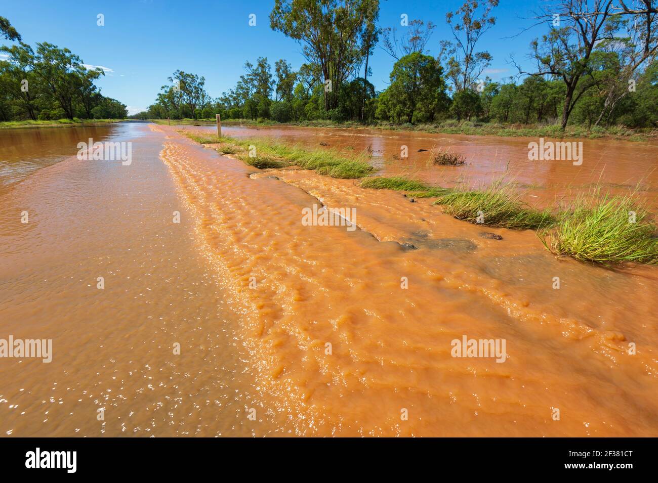 Abgelegene Outback-Straße überflutet und mit rotem Schlamm bedeckt nach einem Sturm, in der Nähe von Thallon, Queensland, QLD, Australien Stockfoto