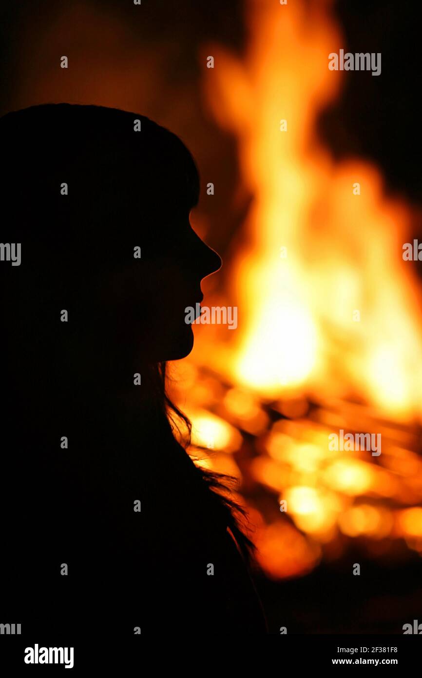 Die Silhouette einer jungen Frau vor einem Großes Feuer Stockfoto