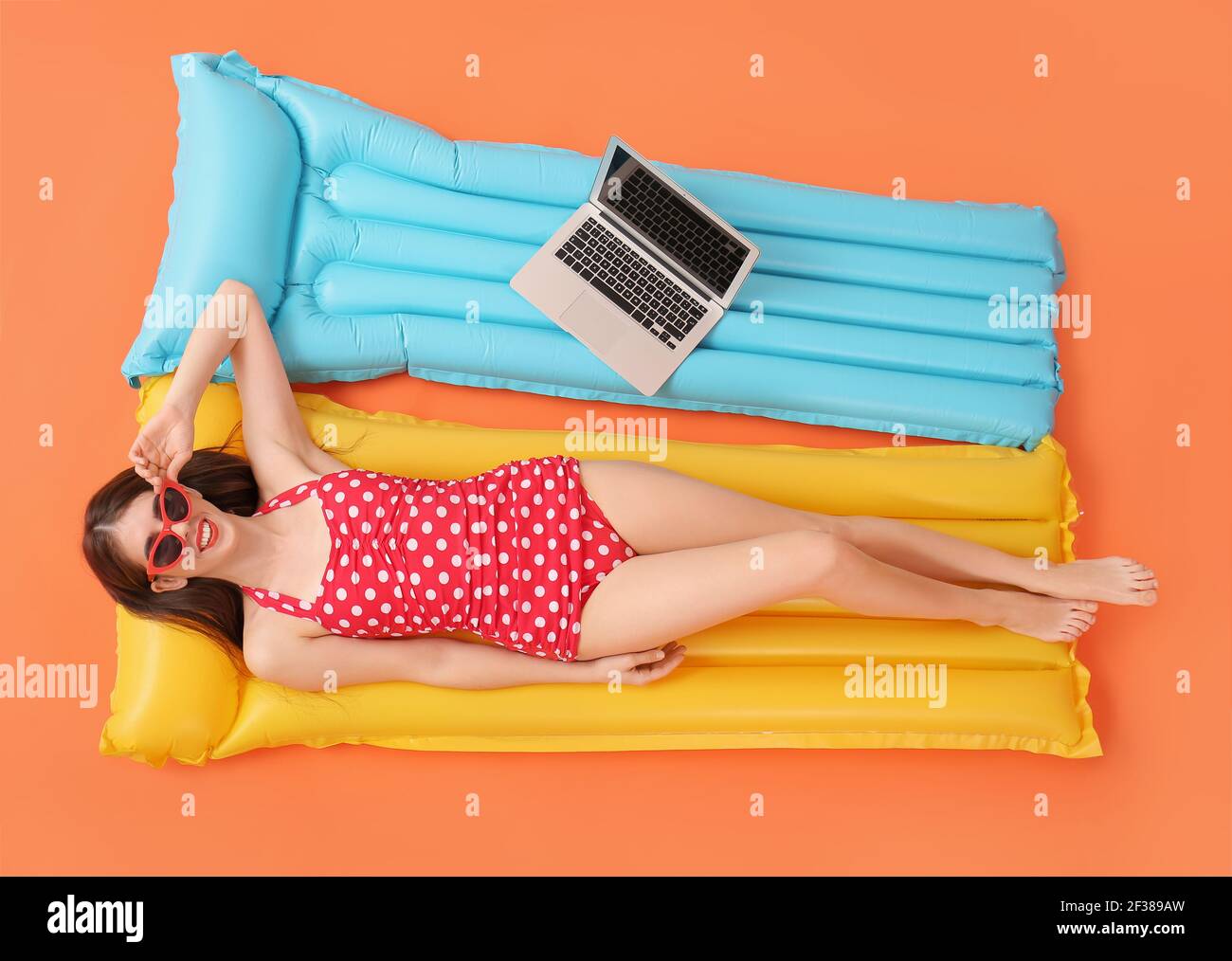 Schöne Frau mit Laptop liegt auf aufblasbare Matratze gegen Farbe Hintergrund Stockfoto