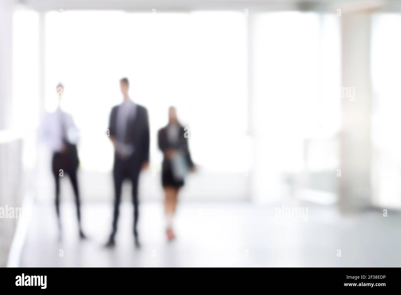 Verschwommene Geschäftsleute stehen in weißen Bürogebäude Halle, kann als Hintergrund verwendet werden Stockfoto