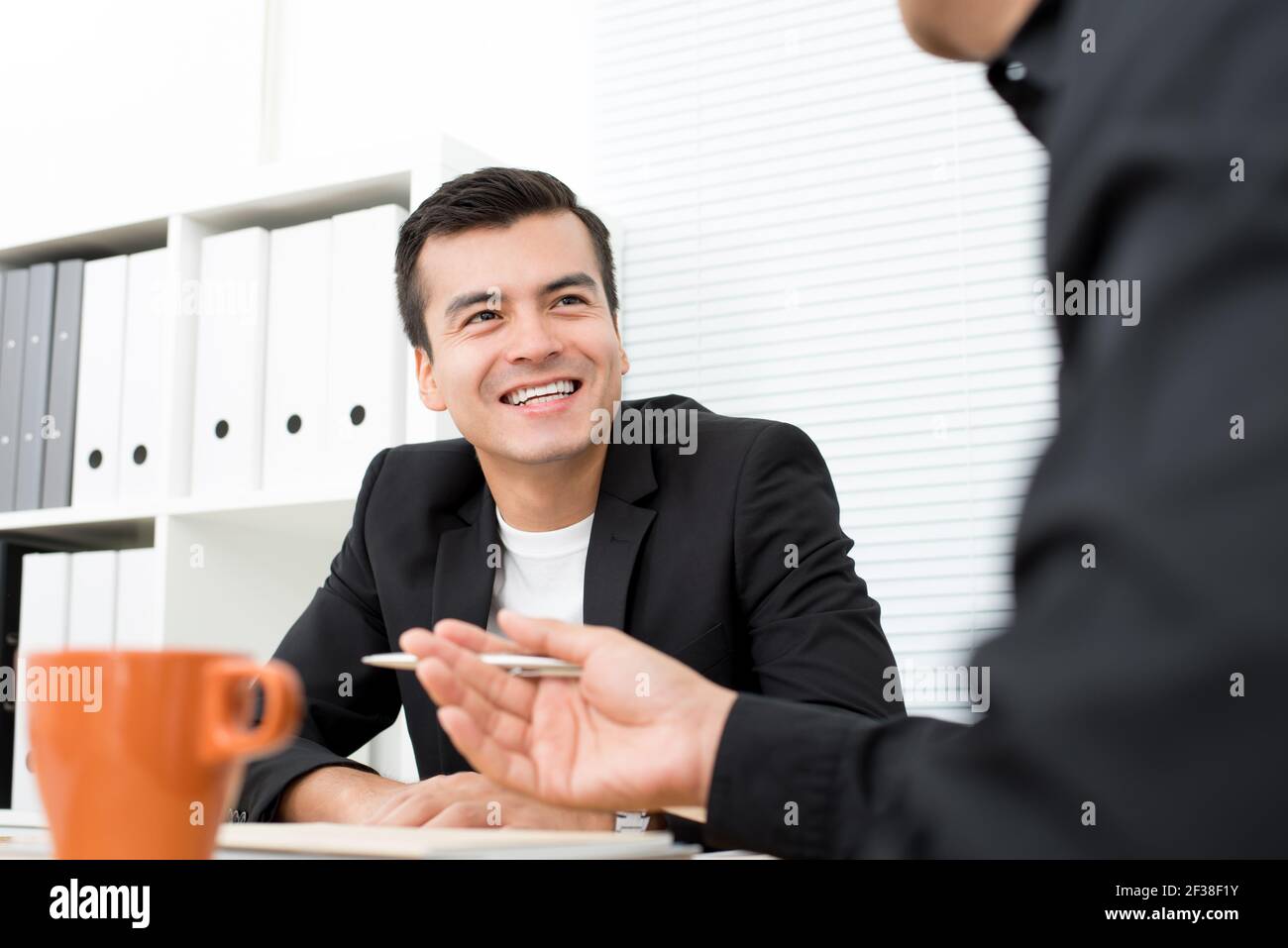 Lächelnder gutaussehender Geschäftsmann in der Sitzung Stockfoto