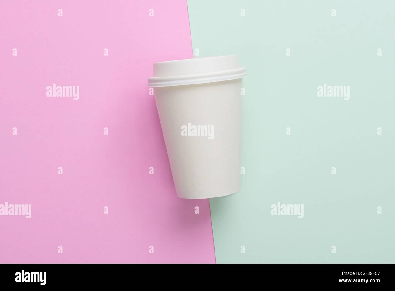 Zum Mitnehmen (zum Mitnehmen) Kaffeetasse auf hellblauem und rosa Hintergrund Stockfoto