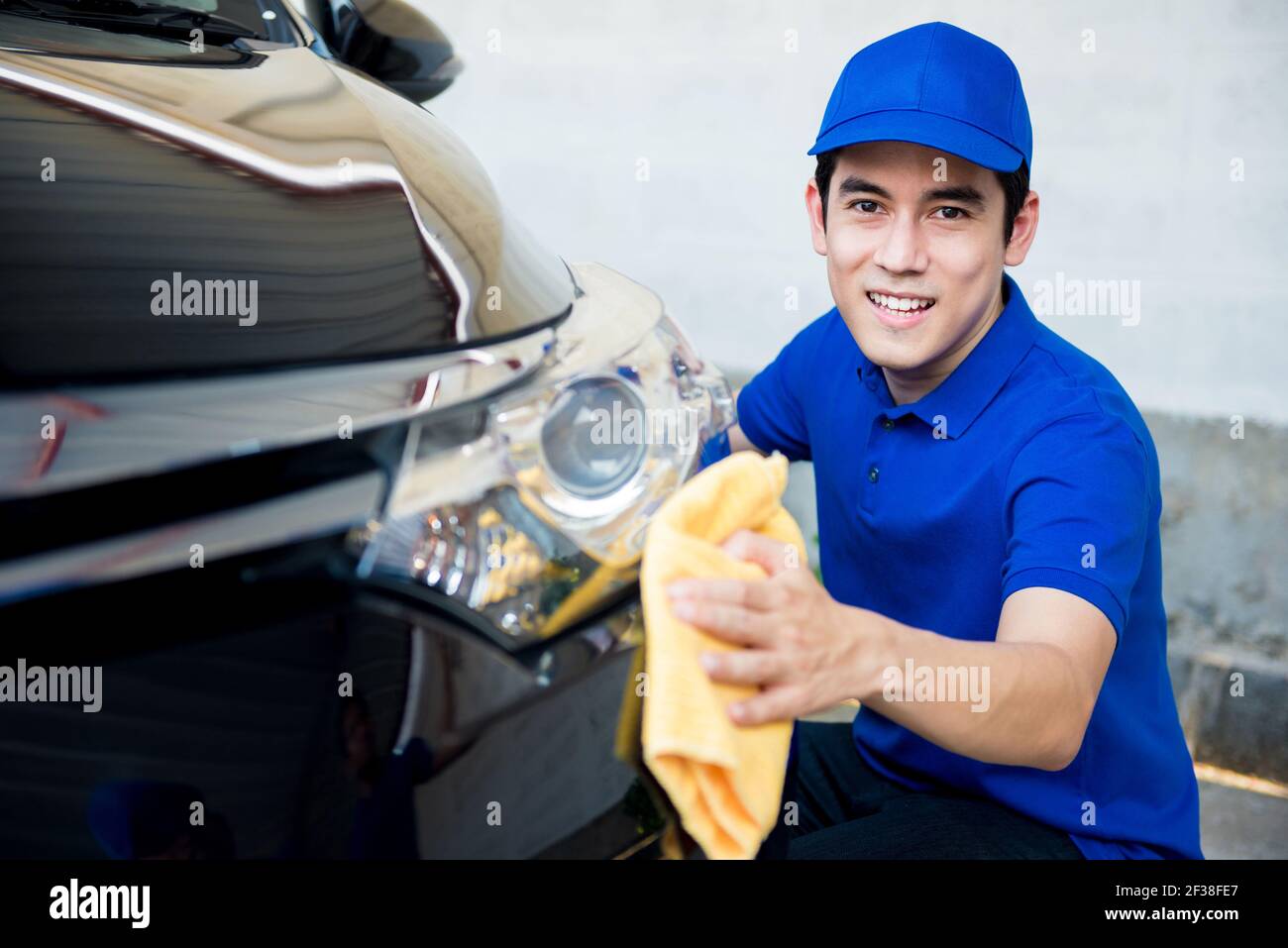 Junger Mann Polieren (Reinigung) Auto mit Mikrofaser Tuch - Auto Detaillierung, Valeting und Auto Service Konzepte Stockfoto