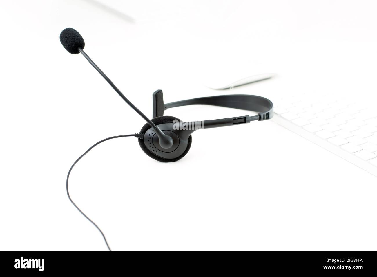 Mikrofon-Headset auf weißem Tisch mit unscharfen Computer-Tastatur Hintergrund - Bediener, Call Center, Kundendienst und Telemarketing-Konzepte Stockfoto