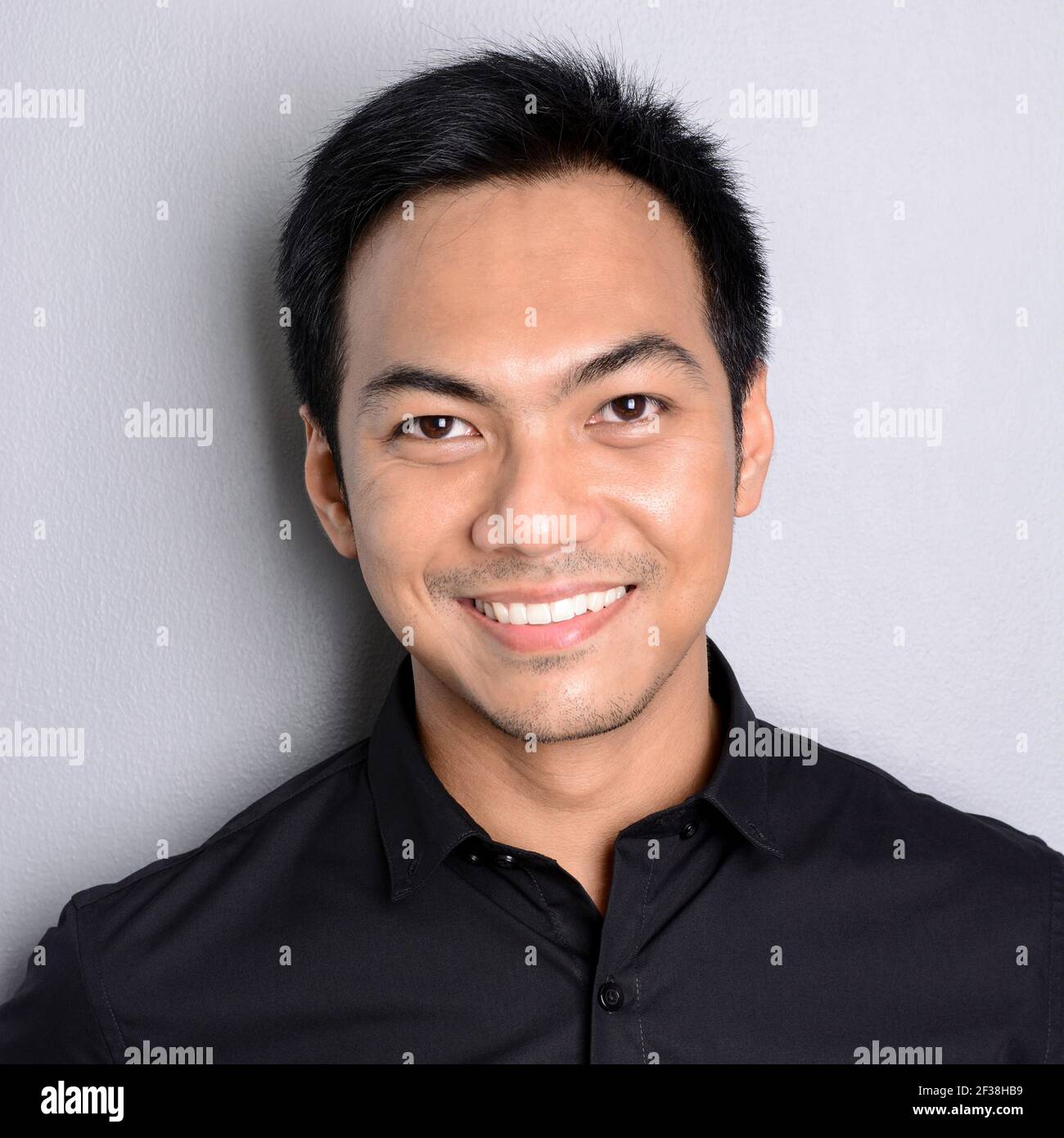 Attraktiver lächelnder asiatischer Mann auf hellgrauem Hintergrund Stockfoto