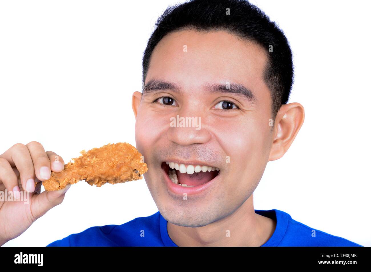 Junger Mann, der gebratenes Huhn isst Stockfoto