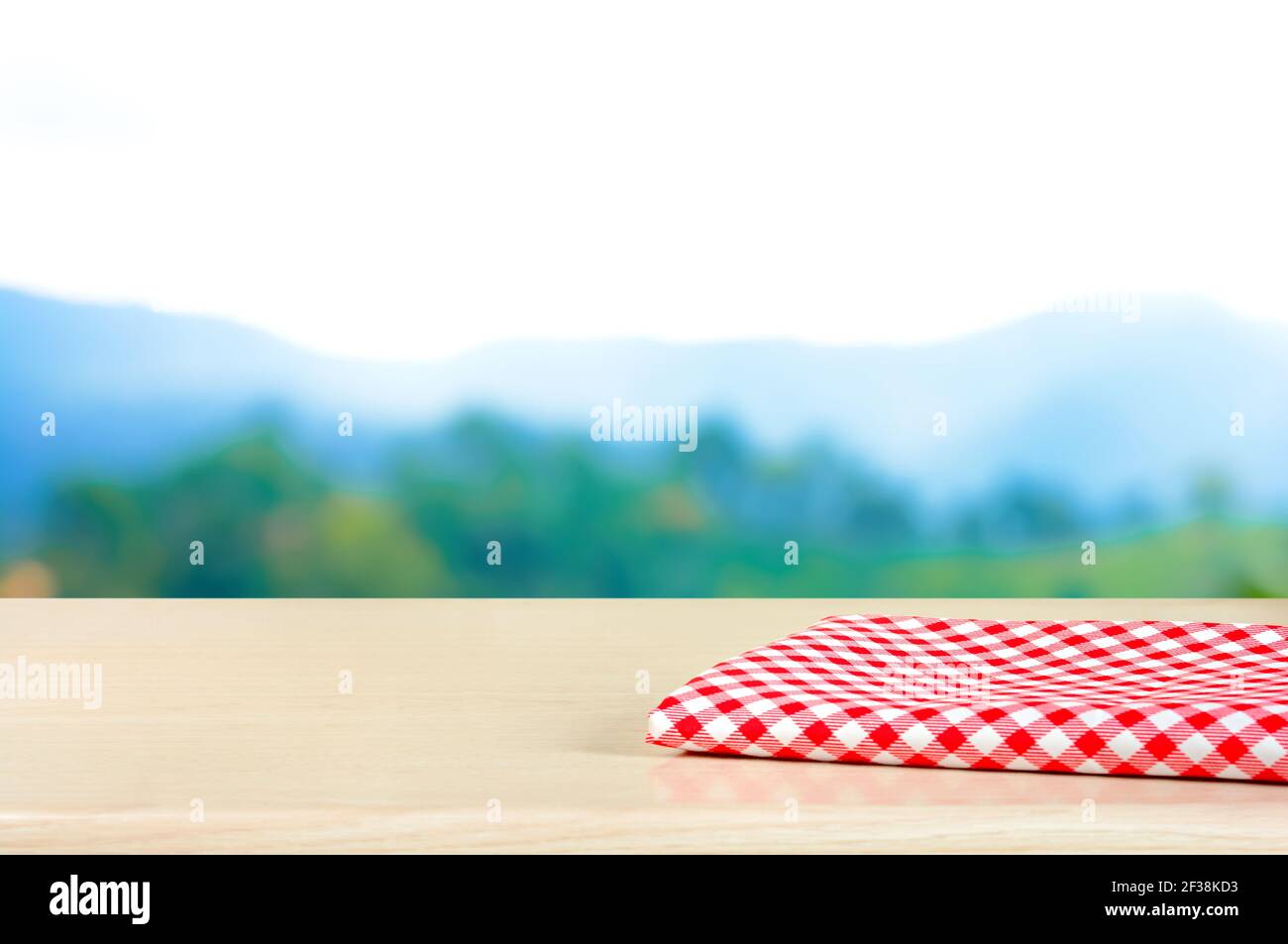 Rot kariertes Tuch auf Holztischplatte in Blur Mountain Hintergrund - kann zur Anzeige oder Montage Ihres verwendet werden Produkte Stockfoto