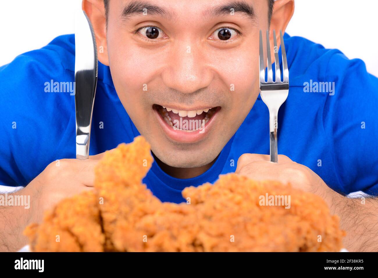 Ein Mann hält Messer und Gabel, starrte auf gebratenes Huhn, zu essen Stockfoto