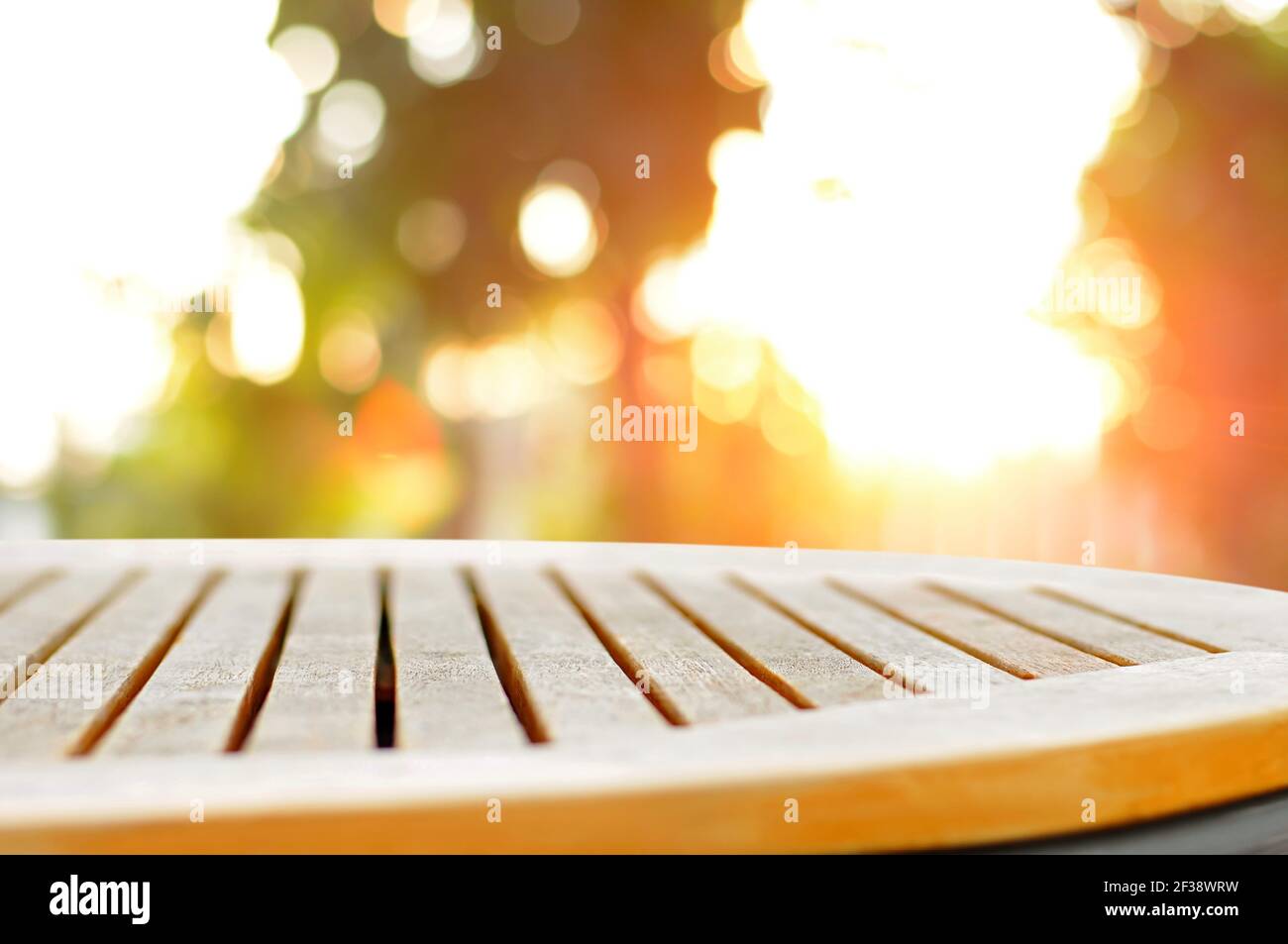 Runde Holztischplatte auf Blur Bokeh Hintergrund des Sonnenlichts Leuchten durch die Bäume - kann zur Anzeige verwendet werden Oder die Montage Ihrer Produkte Stockfoto