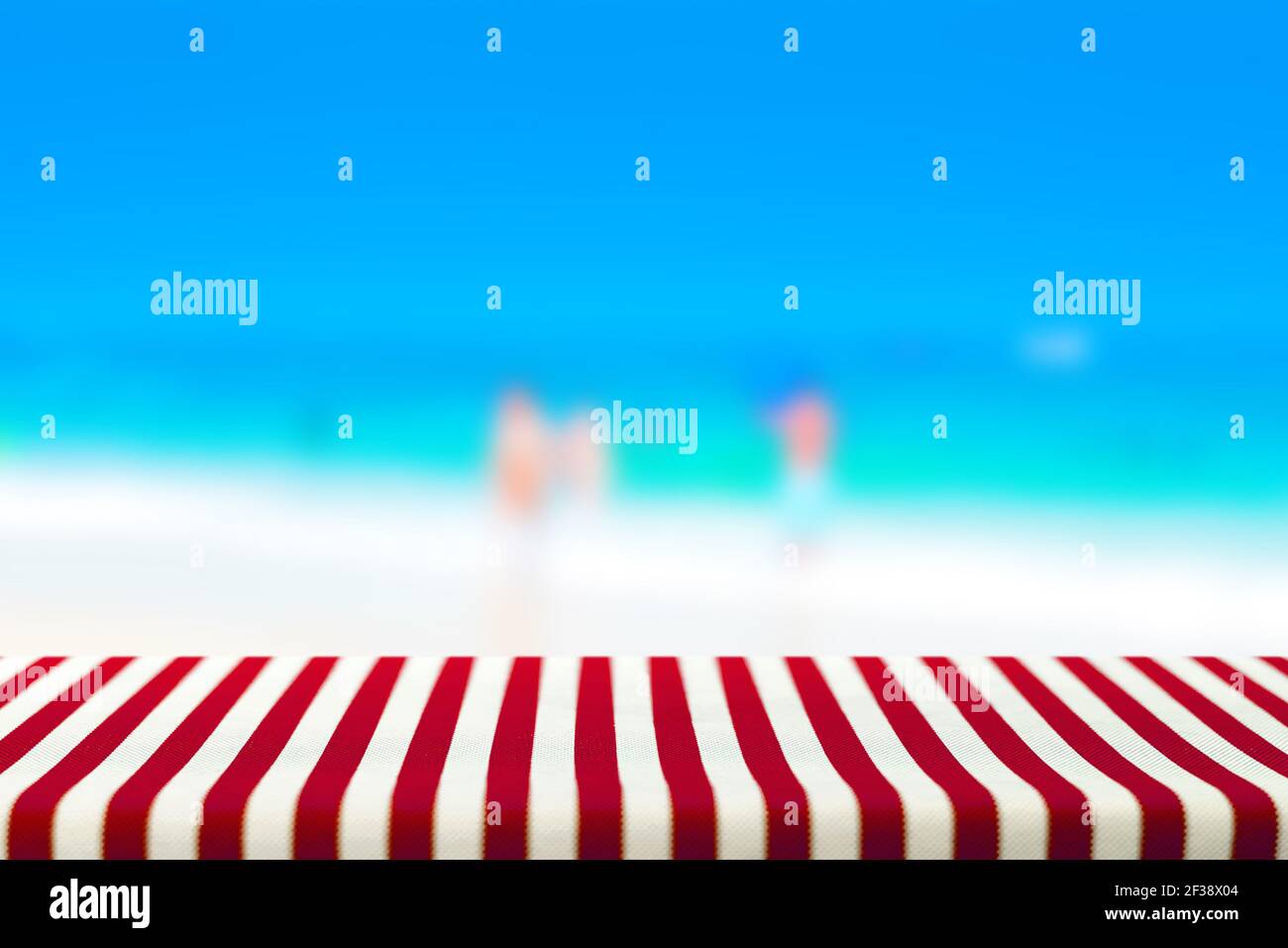Tisch bedeckt mit rot gestreiften Tischdecken im unscharfen Strand Hintergrund - kann zur Anzeige oder Montage Ihrer Produkte verwendet werden Stockfoto