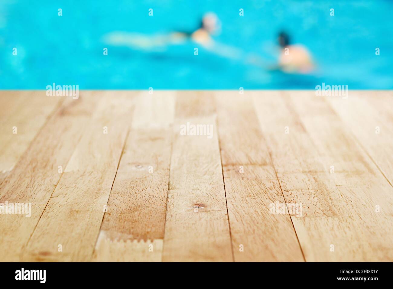 Holztischplatte auf verschwommenem Hintergrund des Swimmingpools mit Wenige Menschen Stockfoto