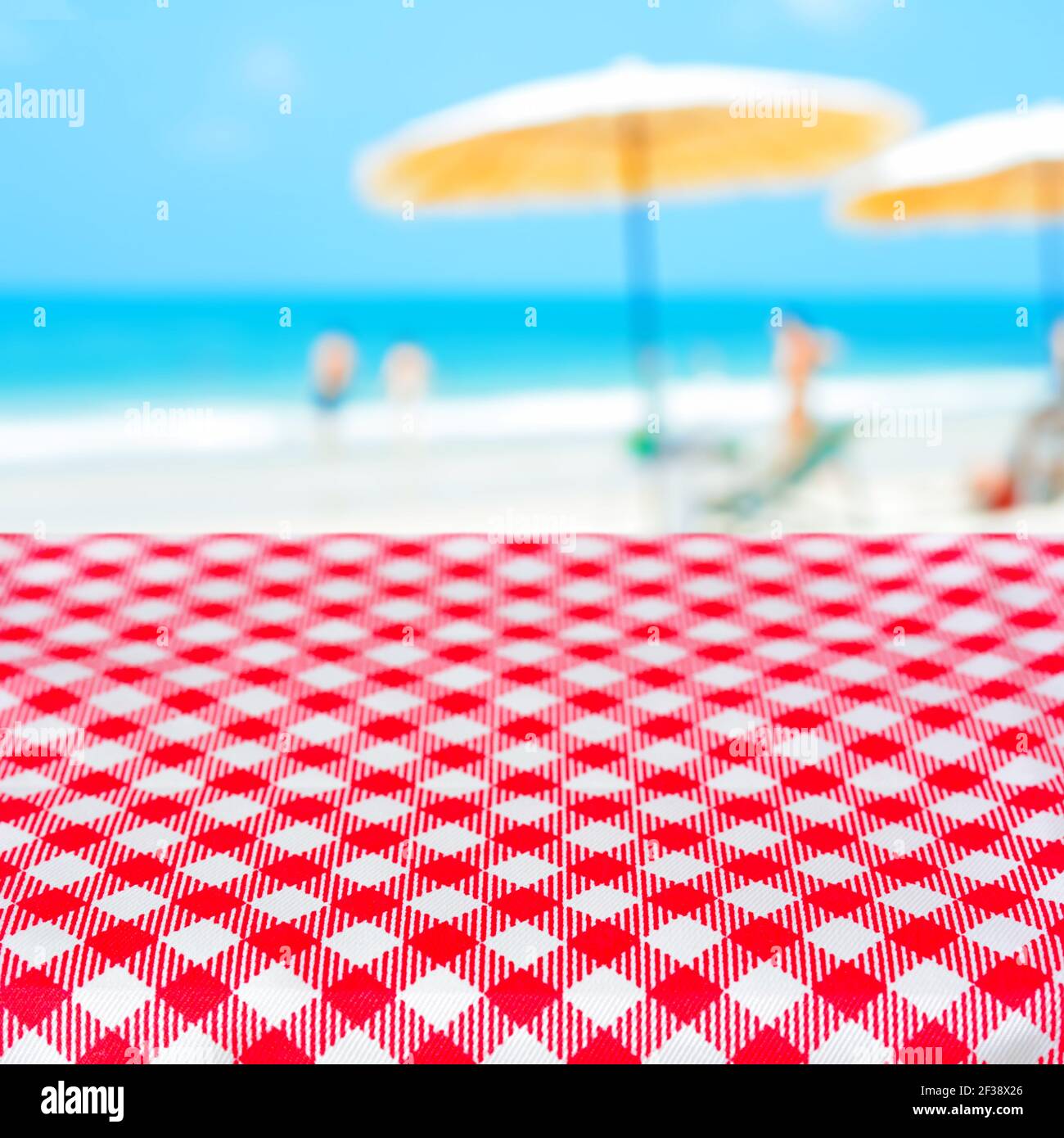 Rote karierte Tischdecke auf verschwommenem Strand Hintergrund, Sommerurlaub Strand Picknick-Konzept - kann für die Anzeige oder Montage Ihrer Produkte verwendet werden Stockfoto