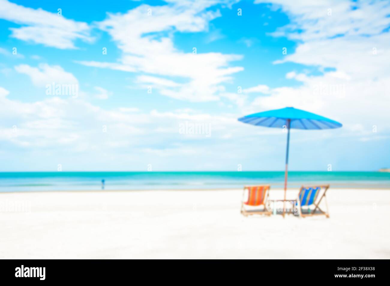 Verschwommenes Bild von Strandliegen und Sonnenschirm auf weißem Sand Strand im Sommer blauen Himmel Hintergrund Stockfoto