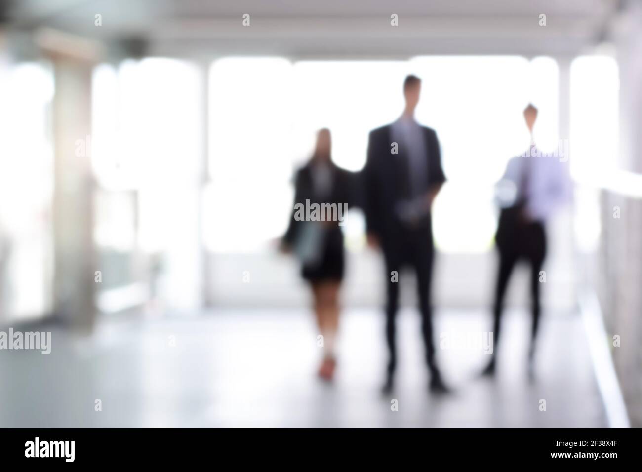 Verschwommene Geschäftsleute, die in der Halle stehen, können als abstrakter Hintergrund verwendet werden Stockfoto