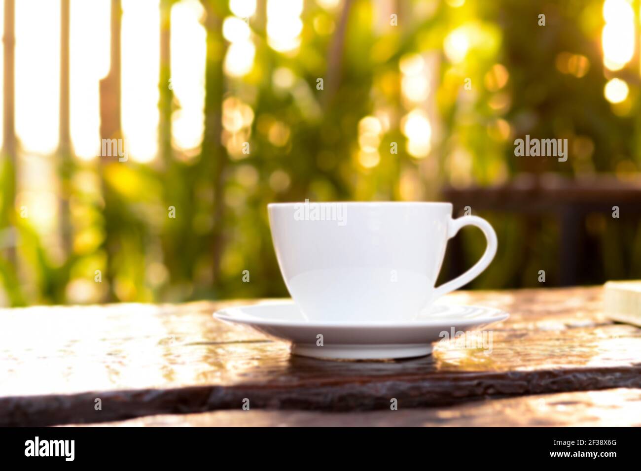 Verschwommene Kaffeetasse auf altem Holztisch in Naturgrün Hintergrund Stockfoto