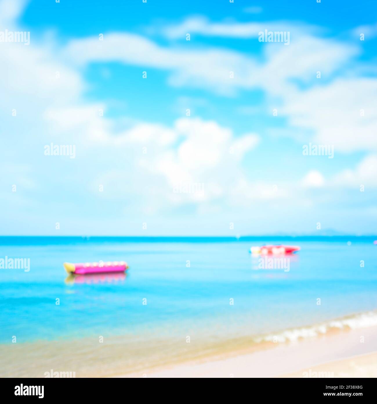 Verschwommener Strand Hintergrund mit Bananenbooten im Meer - Sommer Urlaub Hintergrund Konzept Stockfoto