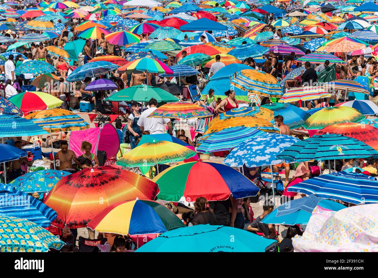 Endlose Schwärme von Menschen und ihre Sonnenschirme packen am 4th. Juli 2017 das Ufer auf Coney Island. Stockfoto