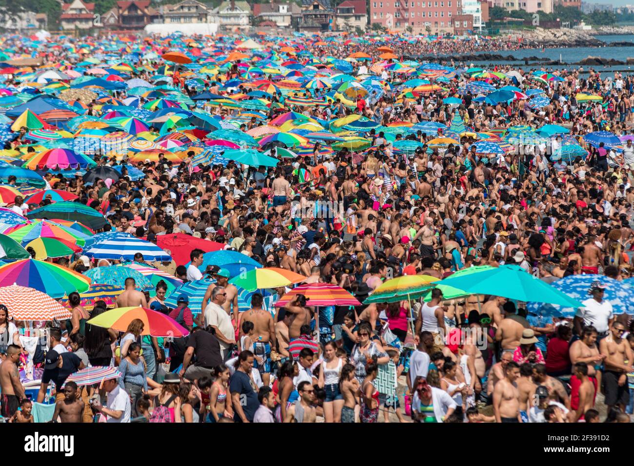 Endlose Schwärme von Menschen und ihre Sonnenschirme packen am 4th. Juli 2017 das Ufer auf Coney Island. Stockfoto