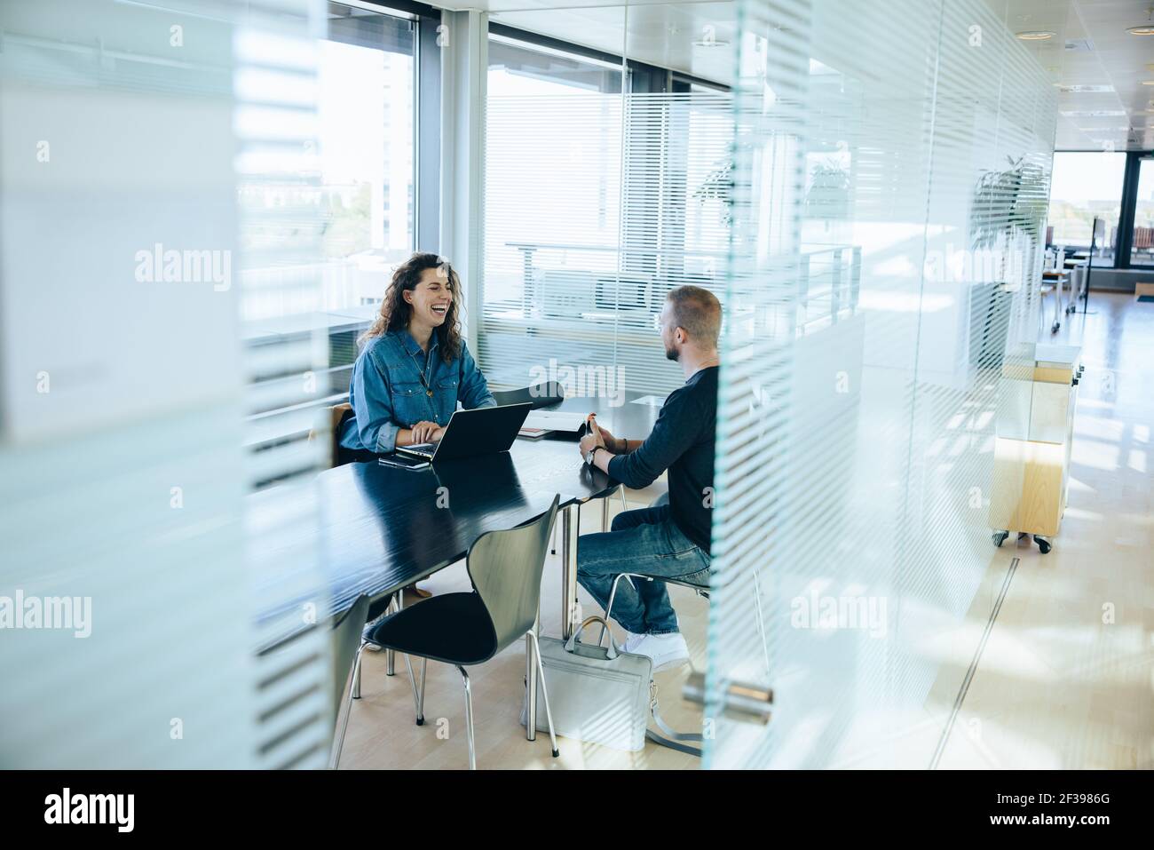 Lächelnde Geschäftsfrau, die Interview mit einem Mann nimmt. Bewerbungsgespräch im Vorstandszimmer. Stockfoto