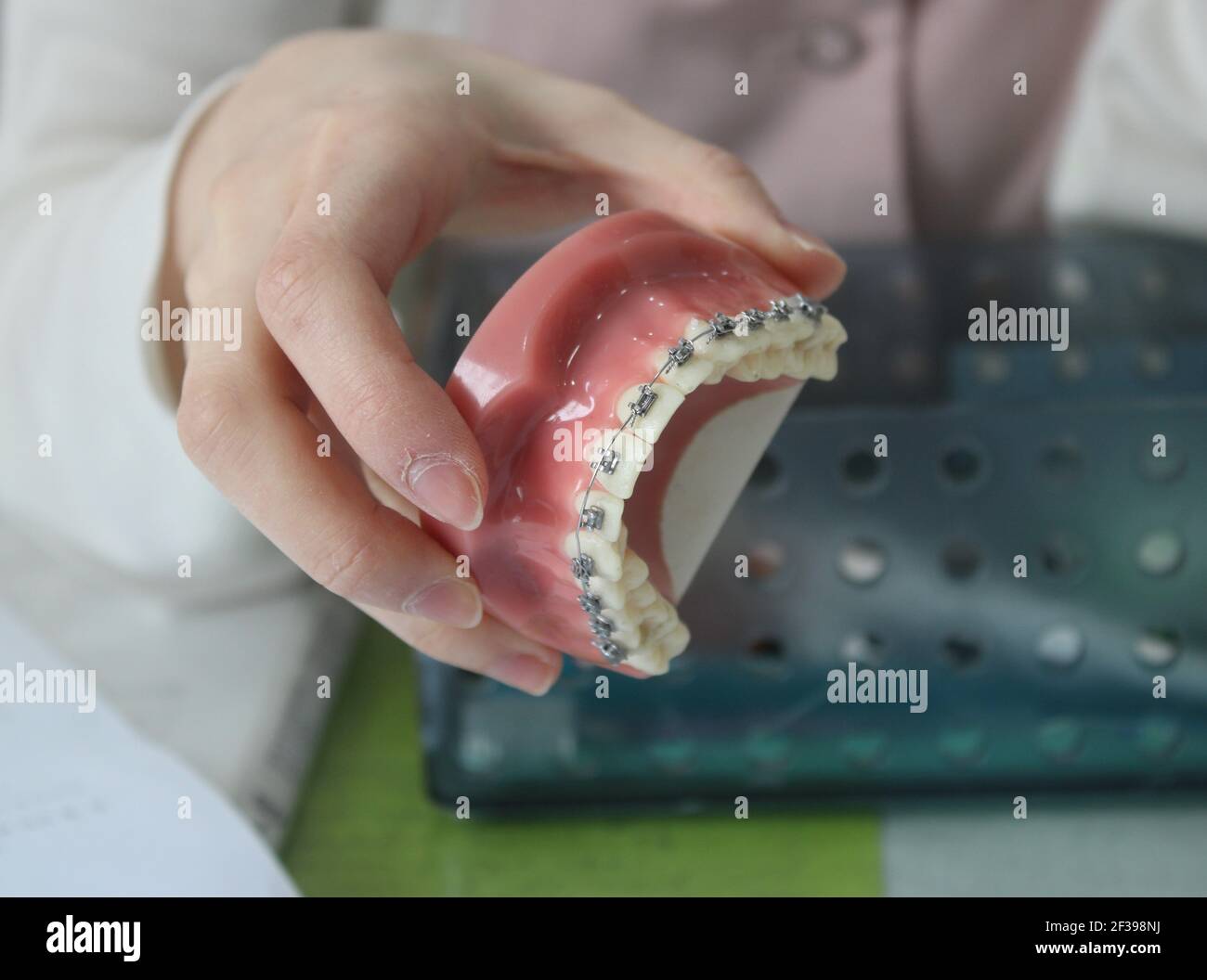 Kieferorthopäde zeigt zahnmedizinisches Modell mit traditionellen Zahnspangen Stockfoto
