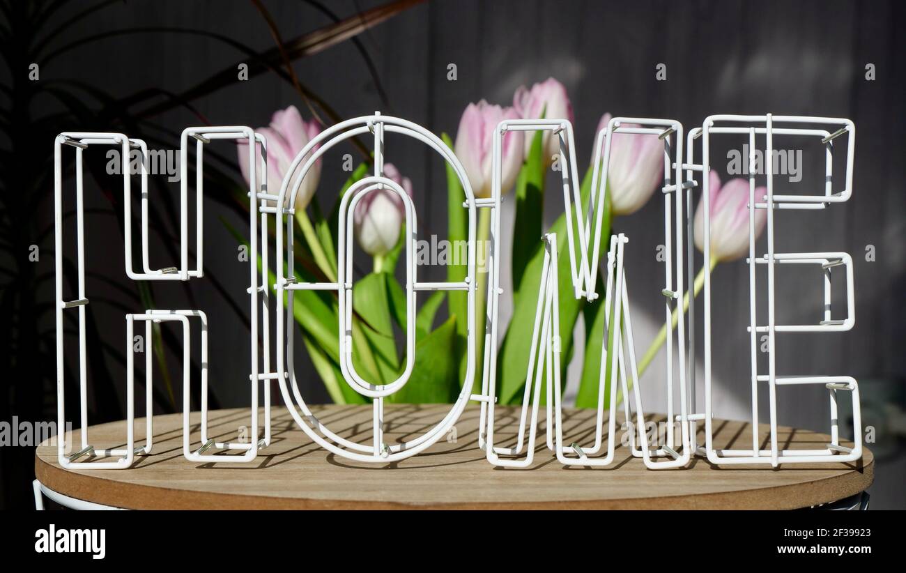 Nahaufnahme von Briefen zu Hause auf dem Hintergrund von rosa Blumen Tulpen an einem sonnigen Tag. Wohnkomfort in kleinen Kleinigkeiten Stockfoto