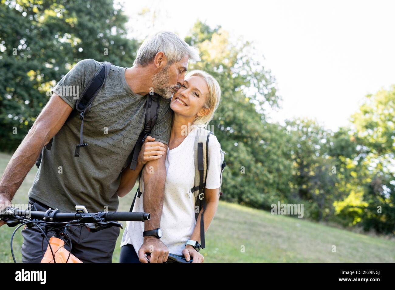 Reifer Mann küsst seine Frau, während er im Wald steht Stockfoto