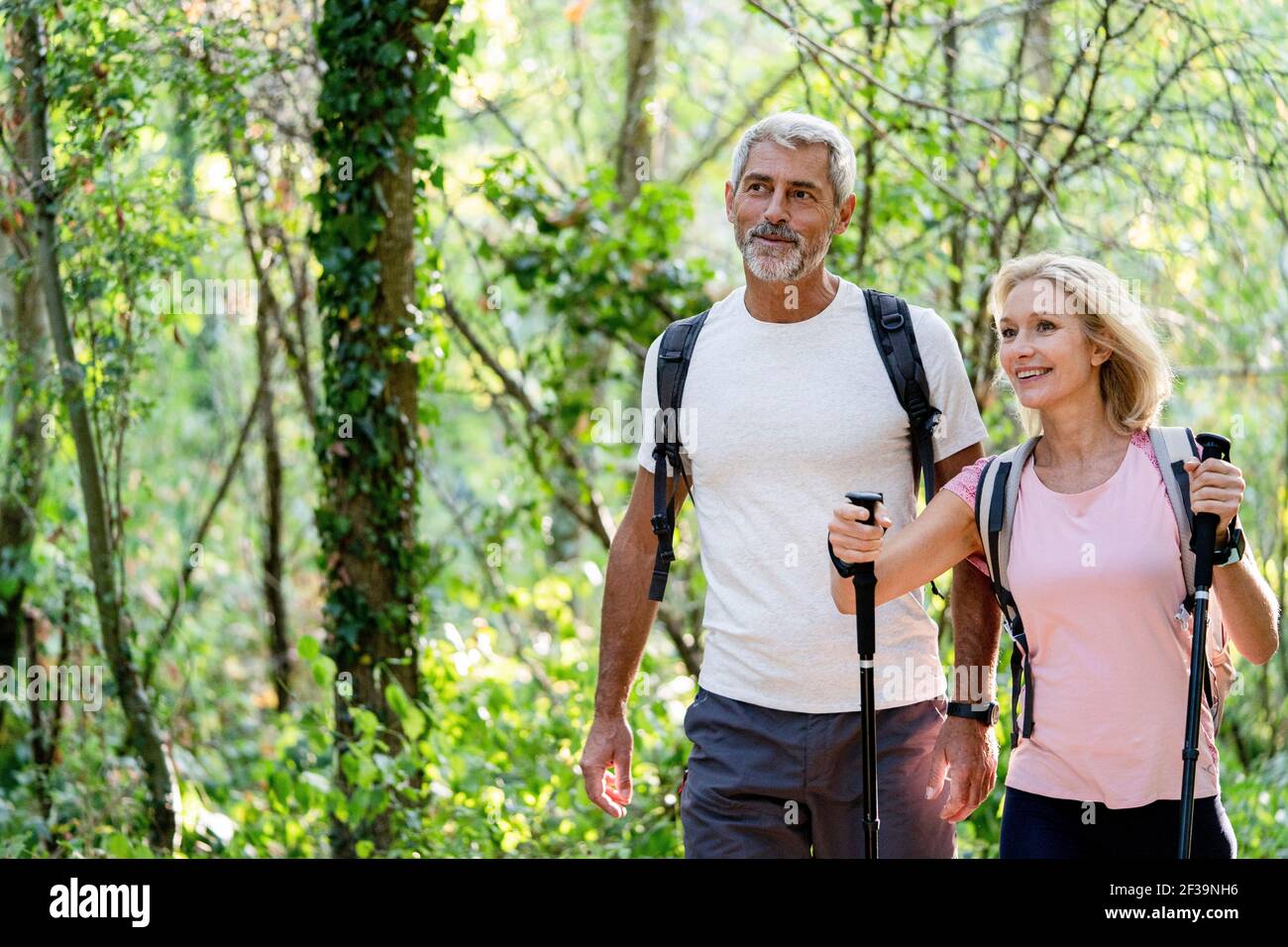 Lächelndes reifes Paar, das beim Wandern im Wald redet Stockfoto