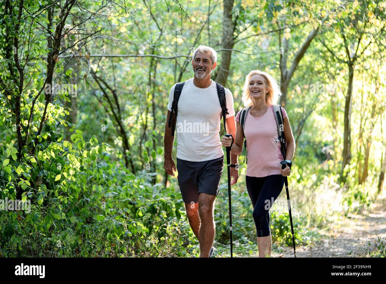 Lächelndes reifes Paar, das gemeinsam im Wald wandert Stockfoto