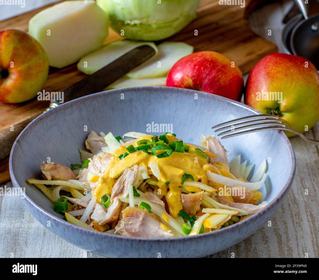 Hausgemachter Hühnersalat mit rohen Äpfeln und Kohlrabi-Streifen serviert Mit einer leckeren Currysauce auf dem Küchentisch Stockfoto