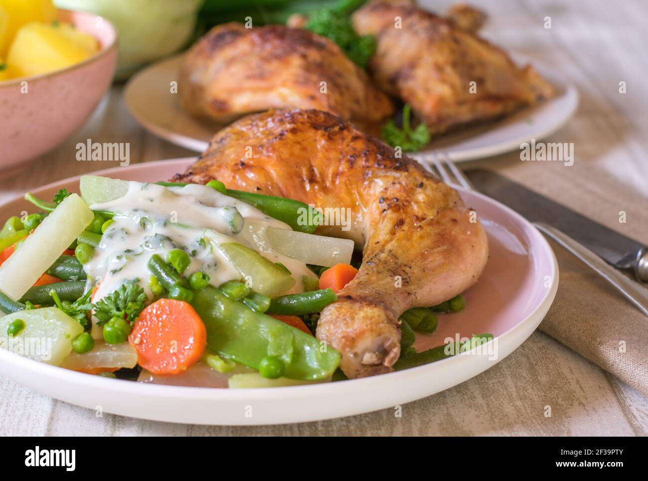 Gebratenes Hähnchenbein mit Frühlingsgemüse und weißer Sauce auf Eine Platte Stockfoto