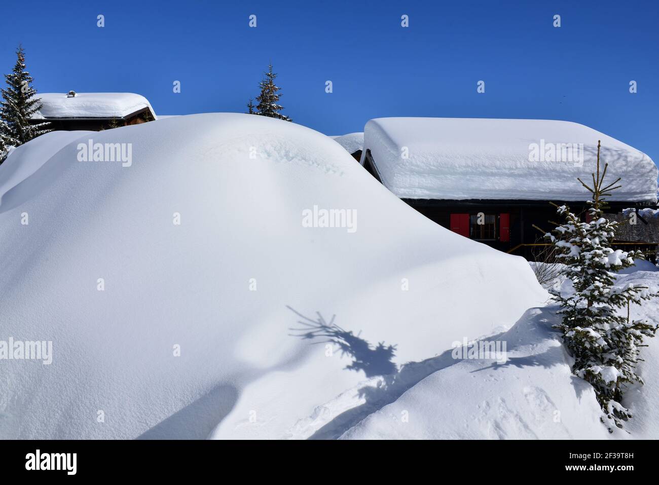 Chalets unter tiefem Schnee mit blauem Himmel Stockfoto